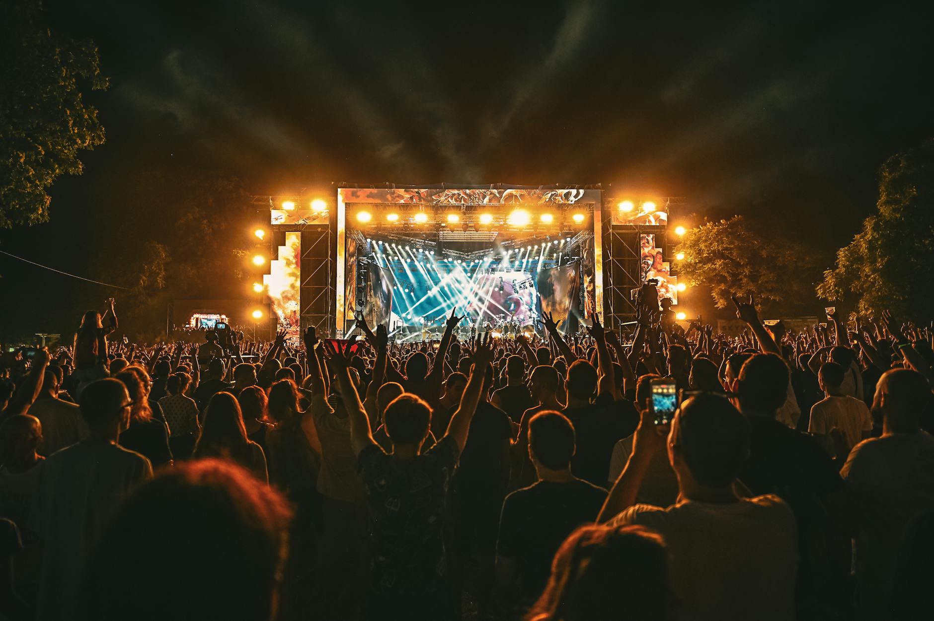 Tłum fanów na nocnym plenerowym koncercie rockowym nad rzeką