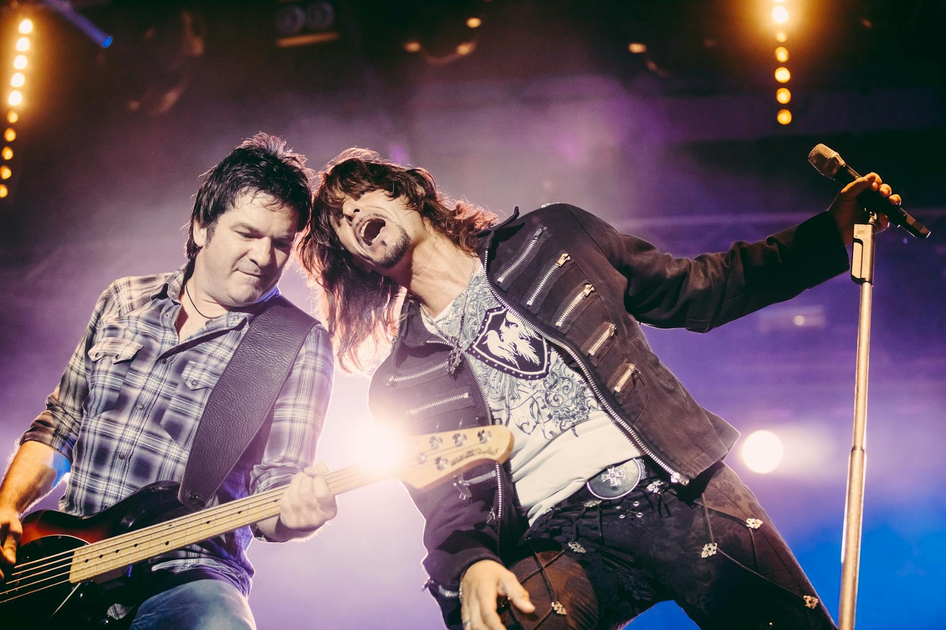 Wokalista i gitarzysta grają energetyczny rock na scenie w ostrym świetle