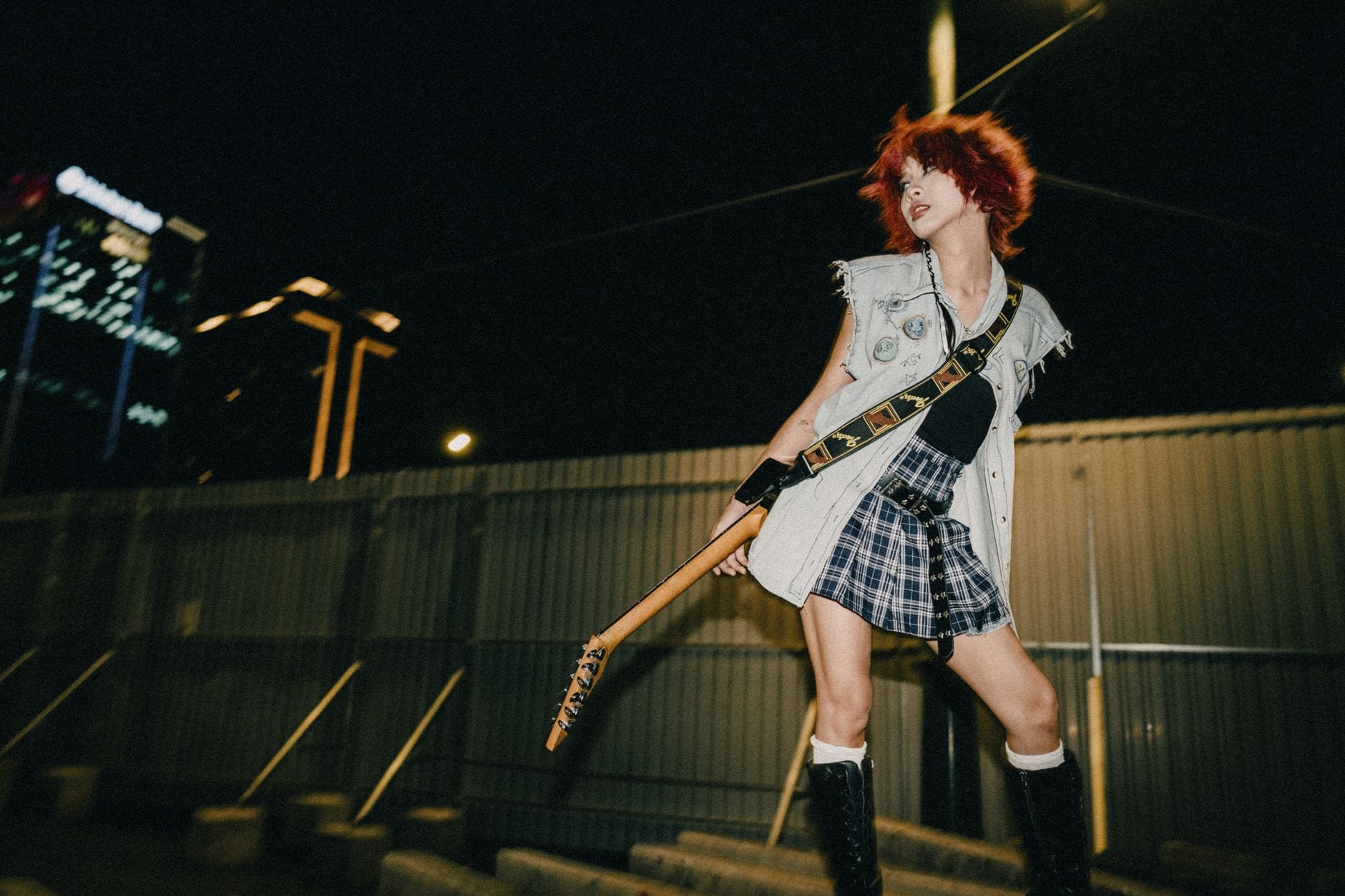 Młoda gitarzystka rockowa z farbowanymi włosami gra nocny koncert