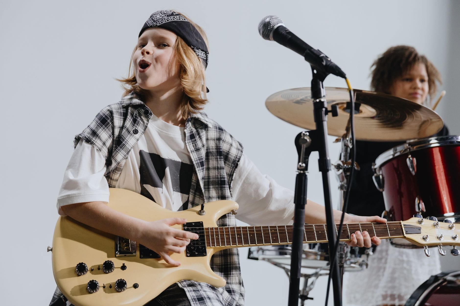Młodzi muzycy rockowi grają na gitarze i perkusji na scenie